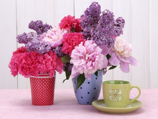 spring flowers and cup on table on white wooden background