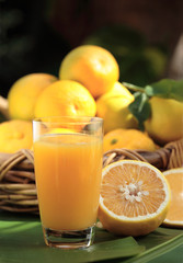 Glass of orange juice with ripe oranges