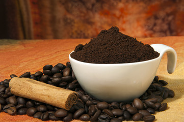 cup with coffee powder and coffee beans scattered