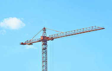 Red construction tower crane against blue sky