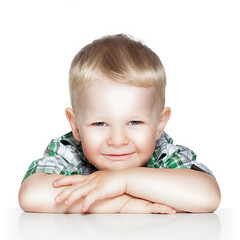 Portrait of a cute little boy smiling while sitting at table, is