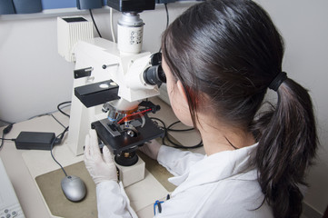 Mujer científico mirando por microscopio