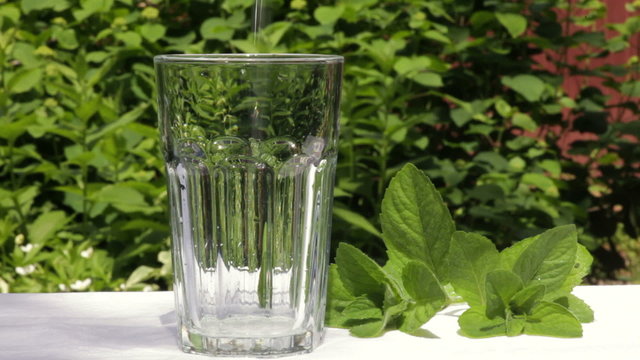 Pouring water into a glass in a summer garden
