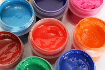 jars with multicolored gouache on white background close-up