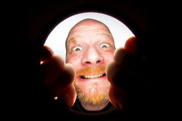 Funny bald man looking down a hole