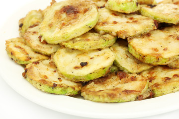 Fried zucchini in a white plate on white background close-up