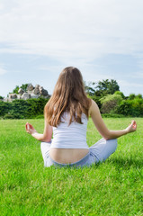 Woman meditates on green lawn on the park