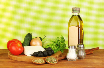 Ingredients for a Greek salad on green cloth background