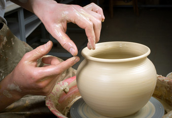 hands of a potter, creating an earthen jar on the circle