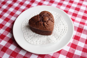Coeur au chocolat sur l'assiette blanche avec nappe carreaux