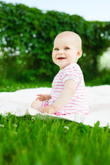 baby girl in striped dress sitting on green grass