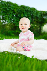 baby girl in dress sitting on green grass outdoors