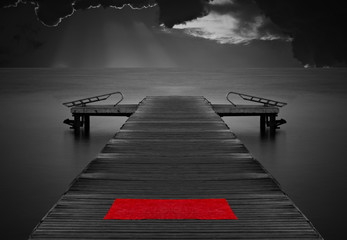 Moody empty jetty with red mat against stormy clouds
