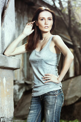 Beautiful young woman model posing near wall of house.