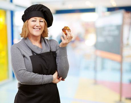 portrait of middle aged cook woman holding a homemade muffin ind