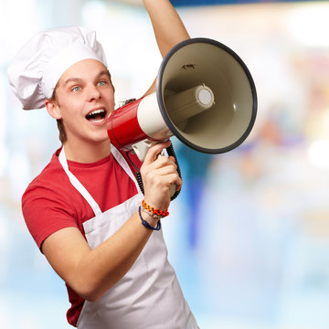 portrait of young cook man shouting with megaphone indoor