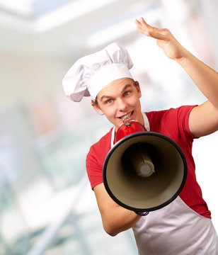 portrait of happy cook man shouting using megaphone indoor