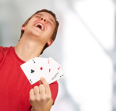 portrait of young man doing a winner gesture playing poker indoo