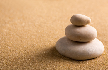 Fototapeta na wymiar Three staked stones on sand