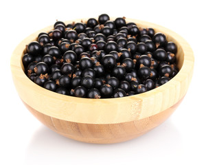 Black currant in wooden bowl isolated on white