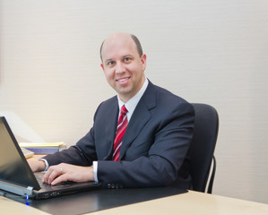 Smiling business man working on a laptop