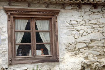 Fototapeta na wymiar Old square wooden window in stone rendered wall of house