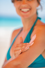 Closeup on female hand applying sun block creme on arm
