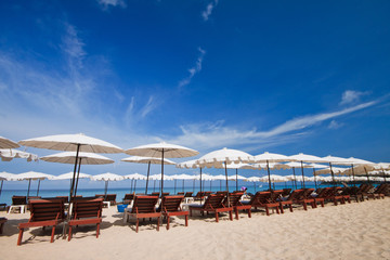 Beach chairs with umbrella and beautiful beach on a sunny day