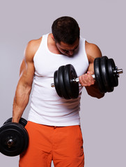 Fit muscular man exercising with dumbbells