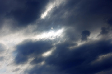 Blue sky and heavy clouds and the sun behind