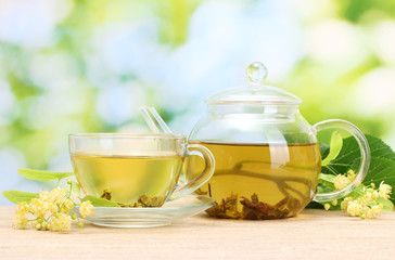 teapot and cup with linden tea  and flowers