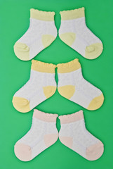 three pairs baby socks on green background