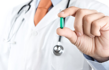 Close up of male doctor holding green pill