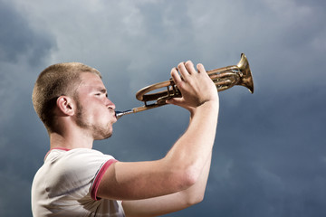 The young man blows the trumpet