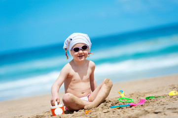 little girl playing with toys in the sand on the beach