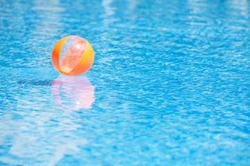 an orange ball in the blue water swimming pool