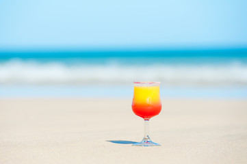 a glass with drink on the beach by the sea