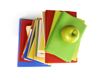 top view of stack of books with green apple