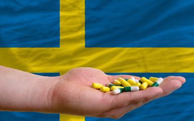Fototapeta premium holding pills in hand in front of sweden national flag