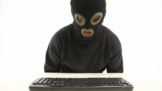 guy in balaclava typing something on the keyboard