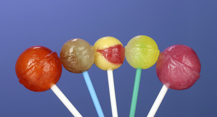 Bright and delicious lollipops on dark blue background close-up