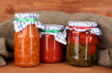 Jars with canned vegetables on wooden background close-up