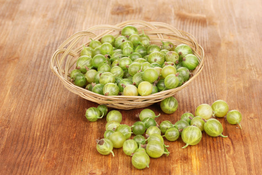 Green gooseberry in basket on wooden background