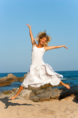 Attractive woman in white jumping outdoors.