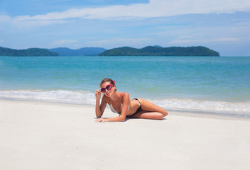 beautiful young woman  in bikini lying on tropical beach