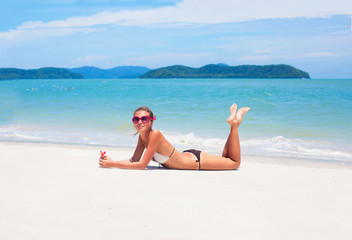 beautiful young woman  in bikini lying on tropacal beach