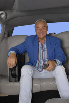 hombre de negocios sujetando un teléfono en un auto.