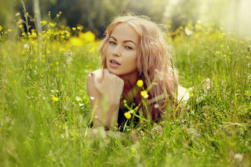 beautiful blond girl on green field with flowers