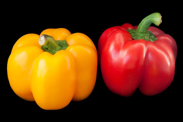 Red and yellow paprika on black background.