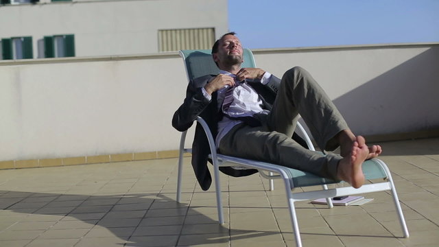 Happy businessman relaxing on sunbeds
